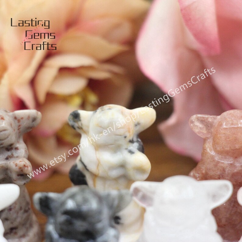 May include: A collection of small, hand-carved stone sheep figurines in various colors, including white, gray, black, and pink. The figurines are all in a praying position with their heads bowed. The text "www.etsy.com/hk-en/shop/LastingGemsCrafts" is visible in the background.