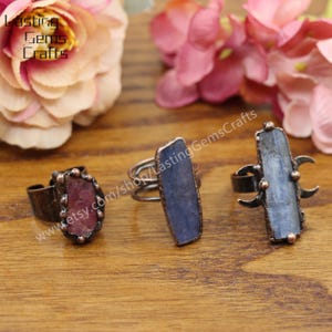 May include: Three rings with different colored gemstones. The first ring has a red gemstone, the second ring has a blue gemstone, and the third ring has a blue gemstone with a crescent moon design.