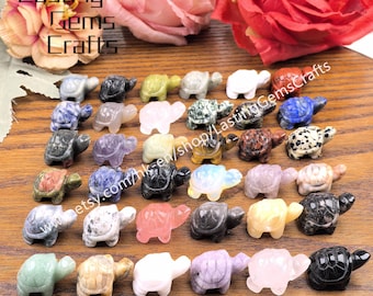 May include: A collection of small, carved gemstone turtle figurines in various colors and patterns. The turtles are displayed on a wooden surface, with the text "Lasting Gems Crafts" visible in the upper left corner.