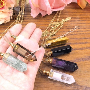 May include: A collection of gemstone pendant necklaces in various colors, including clear, brown, green, purple, black, and yellow. Each pendant is attached to a gold-colored chain. The image includes the text "Lasting Gems Crafts".