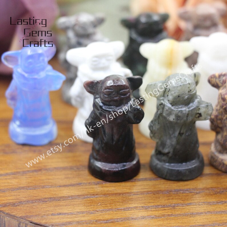 May include: A collection of small, hand-carved figurines of a popular fictional character. The figurines are made from various types of stone, including white, blue, black, and grey. The figurines are all about 2 inches tall and are standing on a wooden surface. The text "www.etsy.com/uk-en/shop/LastingGemsCrafts" is visible in the image.