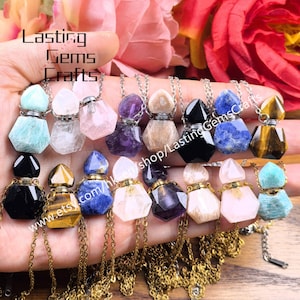 Op de afbeelding: Een verzameling edelsteen hangerkettingen in verschillende kleuren, waaronder blauw, paars en helder. Elke hanger heeft de vorm van een kleine, facetgeslepen fles met een zilverkleurige dop en ketting. De tekst "Lasting Gems Crafts" is zichtbaar.