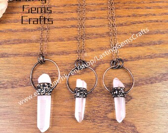 Puede incluir: Tres collares con colgantes de cristal de cuarzo transparente. Cada colgante cuelga de una cadena y un anillo de color bronce. Los cristales están engastados en un engaste metálico decorativo. La imagen incluye el texto "Lasting Gems Crafts" y una dirección web.