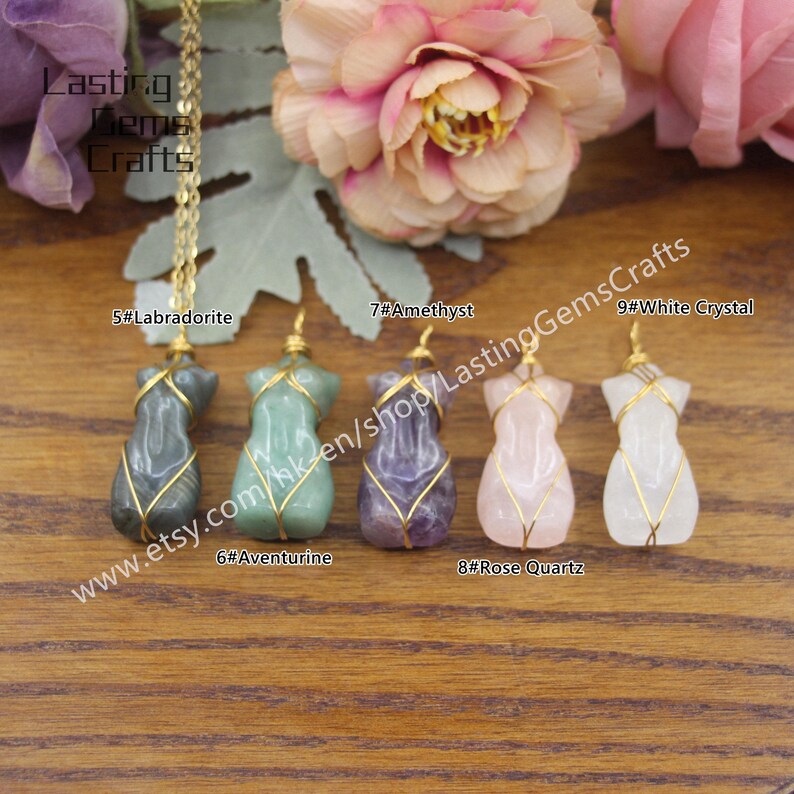 May include: Five different gemstone pendants, each wrapped in gold wire, are displayed on a wooden surface. The pendants are Labradorite, Aventurine, Amethyst, Rose Quartz, and White Crystal. The text "www.etsy.com/hk-en/shop/LastingGemsCrafts" is visible below the pendants.