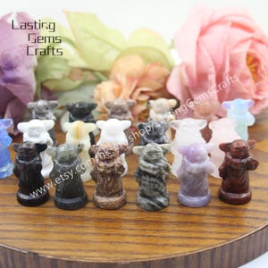 May include: A collection of 17 small, hand-carved Yoda figurines made from various types of stone. The figurines are all about 2 inches tall and are displayed on a wooden surface. The text "www.etsy.com/hk/shop/LastingGemsCrafts" is visible in the image.