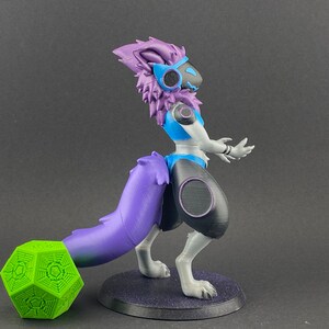 May include: A 3D printed figurine of a purple and white furry creature with a blue and white outfit. The creature has a long purple tail and is standing on a black base. A green geometric object is in the foreground.