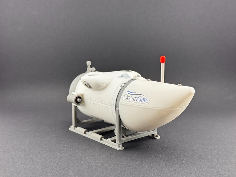 K&ouml;nnte beinhalten: Ein wei&szlig;es U-Boot-Modell mit dem Logo "OceanGate". Es hat eine rote Antenne und steht auf einem grauen St&auml;nder. Das Modell ist ein detaillierter Nachbau eines Tauchboots.