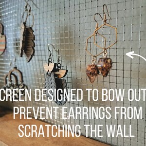 The metal screen is designed to bow out slightly to prevent earrings from scratching the wall.