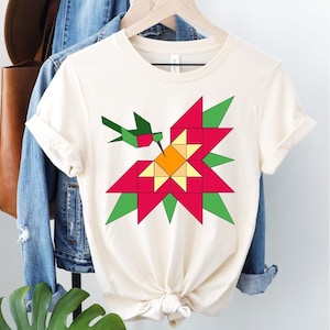 May include: A white t-shirt with a geometric design of a hummingbird and a flower in shades of red, green, yellow, and orange.