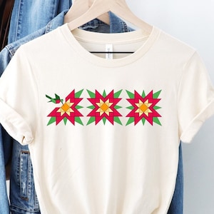 May include: A white t-shirt with a design of three red and green poinsettia flowers with yellow centers.