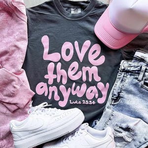 Love them anyway - Luke 23:24. Pink imprint. You can select the color and style of shirt/sweatshirt.