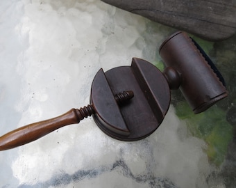 May include: Antique wooden clothes brush with a round base and a handle. The brush has a cylindrical head with a blue fabric strip and a wooden knob on top.