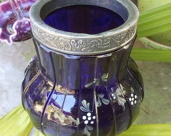 May include: A cobalt blue glass vase with a silver rim and painted floral designs. The vase has a fluted body and a wide mouth.