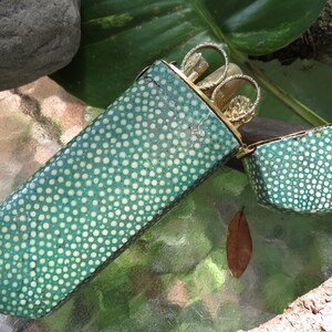 May include: A green and white polka dot case with a gold metal hinged lid. The case is open and contains a set of gold metal manicure tools.