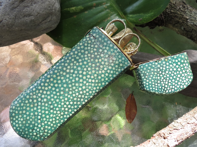 May include: A green and white polka dot case with a gold metal hinged lid. The case is open and contains a set of gold metal manicure tools.