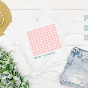 May include: White t-shirt with a pink heart design and the text "100 days smarter."