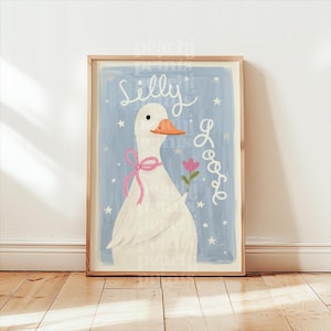 May include: A framed art print featuring a whimsical illustration of a white goose with an orange beak and a pink bow. The goose holds a pink flower against a light blue background with the words "Silly Goose" in white script and stars.