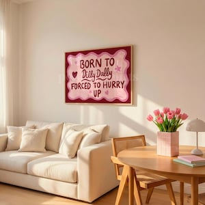 May include: A framed wall art print with the text "BORN TO Dilly Dally FORCED TO HURRY UP" in a playful font. The artwork features a pink and red color scheme with hearts and stars.