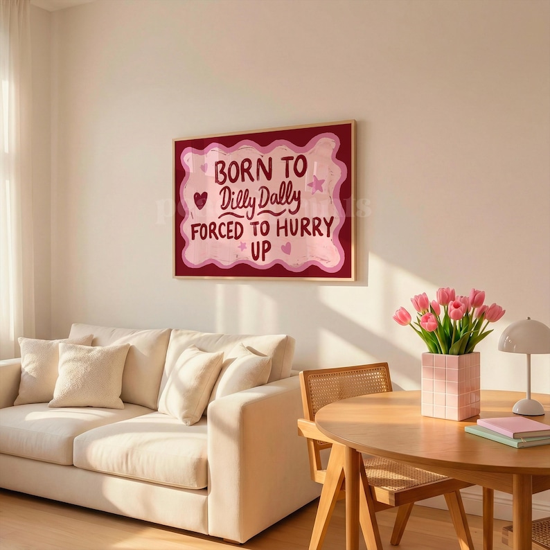 May include: A framed wall art print with the text "BORN TO Dilly Dally FORCED TO HURRY UP" in a playful font. The artwork features a pink and red color scheme with hearts and stars.