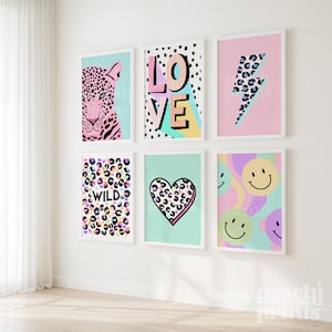 May include: Six framed art prints with colorful designs. The prints feature a leopard, the word "LOVE", a lightning bolt, the word "WILD", a heart, and smiley faces. Each print has a white frame and is mounted on a white wall.