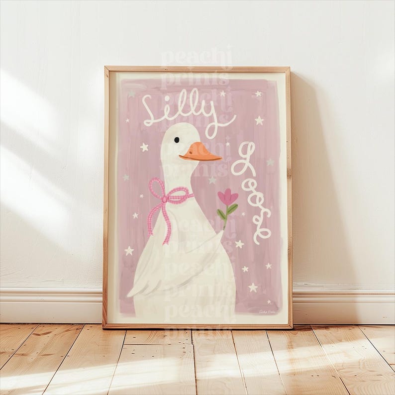 May include: Framed art print featuring a white goose with an orange beak and a pink bow. The goose holds a pink flower and is set against a pink background with the words "Silly Goose" in cursive. The print is in a wooden frame.