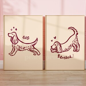 May include: Two framed prints with dog illustrations. One shows a dog with the word "BIG", the other shows a dog stretching with the word "Stretch!". The drawings are in a dark red-brown color on a cream background.
