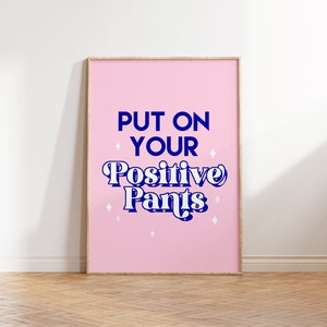 May include: A pink framed poster with the text "Put on your Positive Pants" in blue lettering with white stars.