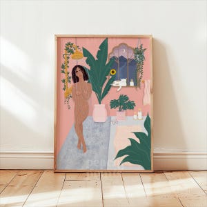 May include: A framed art print featuring a woman in a shower, with a pink background. The artwork includes plants, a cat, and a window scene. The word "peace" is visible in the lower left corner. The print is in a wooden frame.