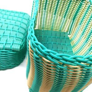 May include: Two woven baskets, one is teal and the other is teal and cream striped. The baskets are made of plastic and have a woven pattern.
