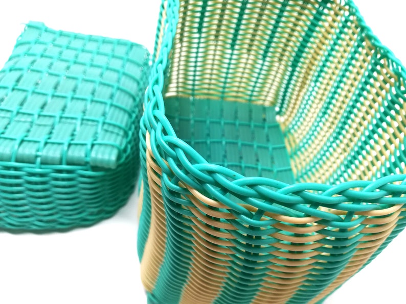 May include: Two woven baskets, one is teal and the other is teal and cream striped. The baskets are made of plastic and have a woven pattern.
