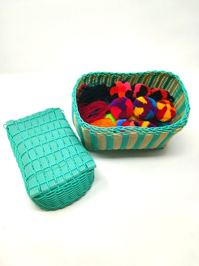 May include: Two turquoise woven baskets, one with a lid, filled with colorful yarn pom-poms. The baskets have a striped pattern.