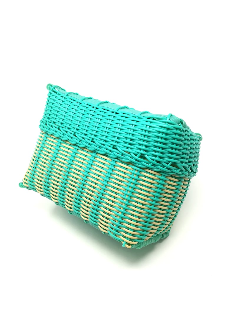 May include: A woven basket with a teal blue and cream striped pattern. The basket is made of plastic and has a rectangular shape.