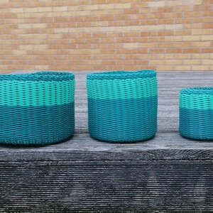 May include: Three woven plastic baskets in different sizes. The baskets are teal and light green in colour.