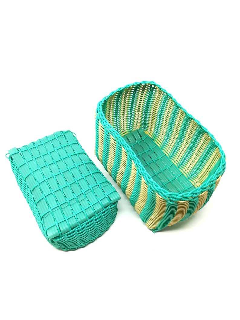 May include: Two woven plastic storage baskets with a green and yellow striped pattern. The baskets are empty and are sitting on a white background.