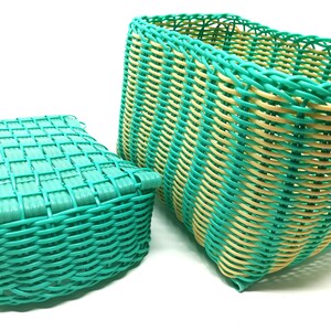 May include: Two woven plastic baskets, one green and one green and yellow. The green basket is smaller and has a square shape. The green and yellow basket is larger and has a rectangular shape.