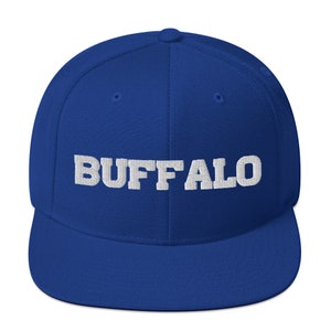 Könnte beinhalten: Königsblaue Baseballkappe mit dem Wort "BUFFALO" in weißen Blockbuchstaben auf der Vorderseite gestickt. Die Kappe hat einen flachen Schirm und eine strukturierte Krone.