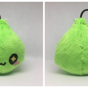 May include: A green plush toy shaped like a teardrop with a cute face and sparkly eyes. The toy has a black string attached to the top and a small green pom-pom on the end of the string.