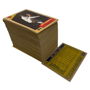 May include: A stack of vintage baseball trading cards. The top card features a player in a baseball uniform. The cards have a wood-grain border and the name "DAVE RIGHEITI" is visible. The back of a card is also visible.