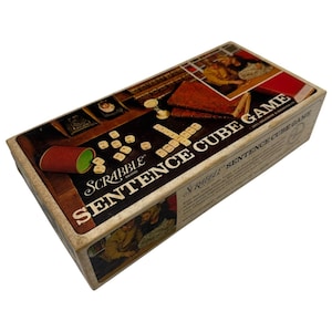 May include: A vintage Scrabble Sentence Cube Game box. The box has a dark brown background with the game title in large white letters. It includes a red dice cup, wooden letter tiles, and illustrations of people playing the game.