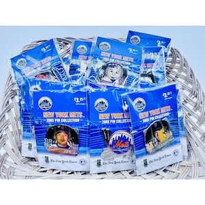 Puede incluir: Una colección de pines de béisbol New York Mets 2005 en embalaje azul. Los pines presentan retratos de jugadores y el logotipo de los Mets. El embalaje incluye el texto "New York Mets 2005 Pin Collection" y "The New York Times".