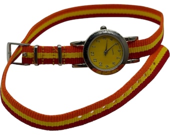 Reloj japonés de cuarzo con esfera amarilla y correa de nailon a rayas naranjas.