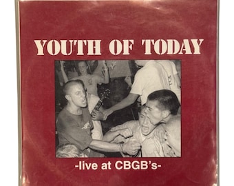 Op de afbeelding: Een vierkante vinylhoes met een dieprode achtergrond. De witte tekst luidt YOUTH OF TODAY bovenaan en -live at CBGB's- onderaan. Een centrale zwart-witfoto toont een band die optreedt op een podium.