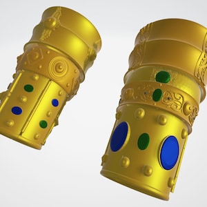 Puede incluir: Dos pulseras de metal de color dorado con diseños intrincados, piedras preciosas azules y verdes y una superficie texturizada.