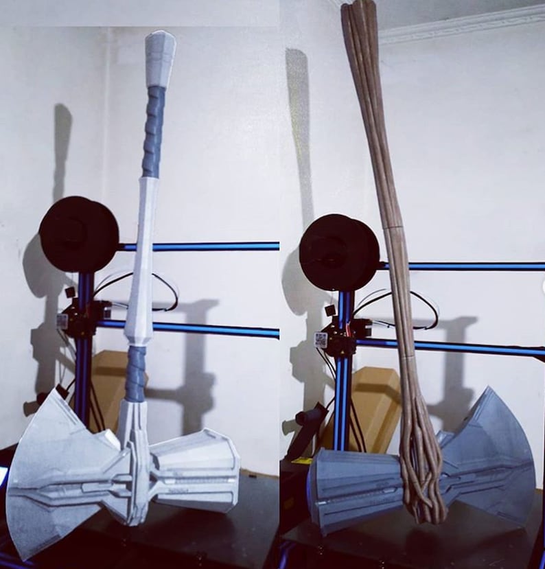 May include: A gray and white prop hammer with a twisted gray handle. The hammer head has a detailed design. The handle is approximately 36 inches long. The prop is displayed next to a brown, wooden-like prop.