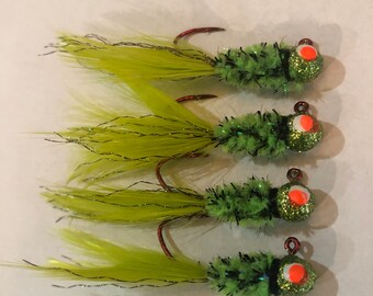 May include: Four green and chartreuse fishing lures with red and orange eyes. The lures have a fluffy, fuzzy texture and are tied to a hook.