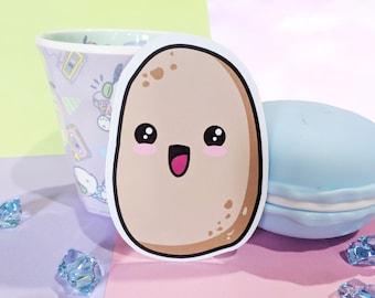 May include: A brown potato sticker with a cute cartoon face. The potato has a big smile and small eyes. The sticker is on a light pink surface.