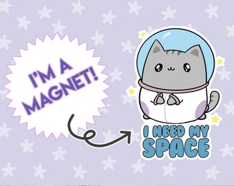 May include: A cartoon cat wearing a white astronaut suit with a blue helmet and a gray face. The cat is holding its hands in front of it. The cat is surrounded by yellow stars. The text "I'm a magnet!" is in a purple speech bubble with a black outline. The text "I need my space" is in a blue speech bubble with a black outline.