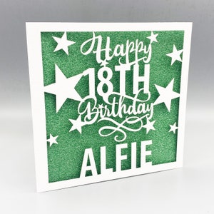 May include: A white card with a green glitter background. The card has a cut-out design of stars and the text "Happy 18th Birthday Alie"
