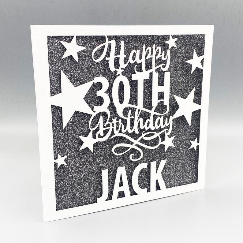 May include: White card with a black glitter background and a white cut-out design that says "Happy 30th Birthday Jack" with stars around the text.