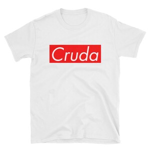 May include: White t-shirt with a red box and the word "Cruda" in white text.